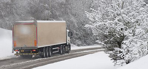 Lorry driving through the snow along a well-cleared road