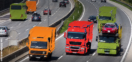 Red, amber and green heavy vehicles driving along a motorway