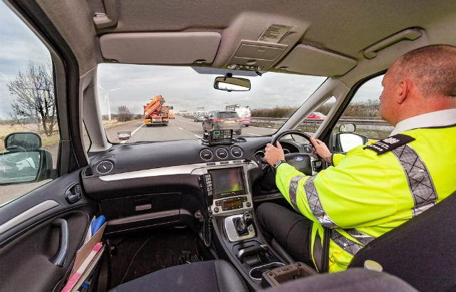 A DVSA enforcement officer driving a car on the motorway