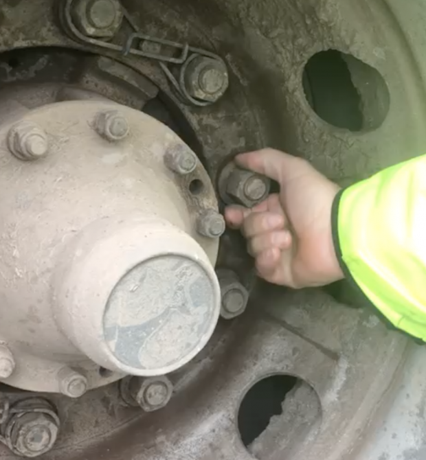 an examiner checking bolts on a wheel